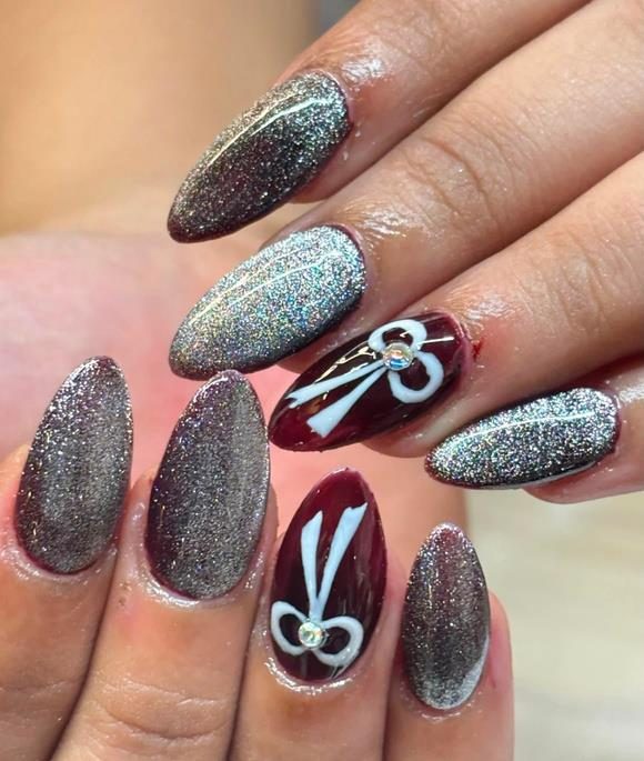 Glitter and maroon nail extensions with hand-painted bow art